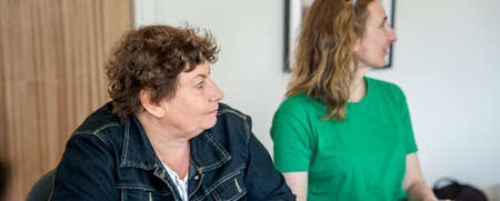 Två kvinnor sitter vid ett bord och antecknar under ett möte eller en workshop.