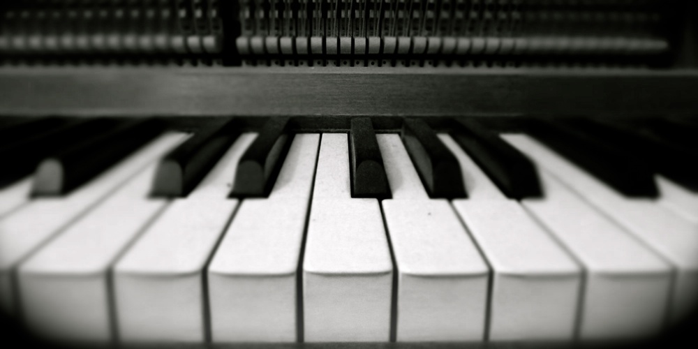 Närbild av pianotangenter i svartvitt, med fokus på de vita och svarta tangenterna.
