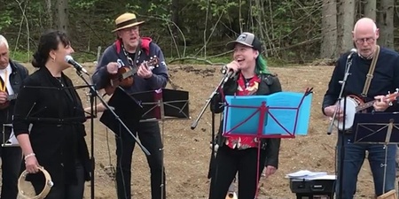 Ett band spelar utomhus med olika instrument, inklusive tamburin, ukulele och banjo.
