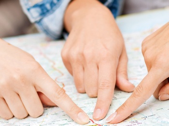 Två personer pekar med sina fingrar på olika platser på en papperskarta.