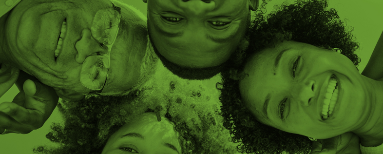 Fyra personer ligger i en cirkel och ler mot kameran, bilden har ett grönt filter.