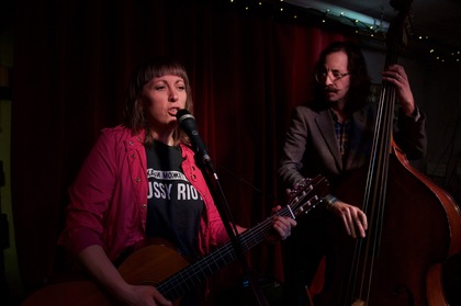Maud Lindström och Petter Eriksson, musiker uppträder på scen, Maud sjunger och spelar gitarr, Petter spelar kontrabas.