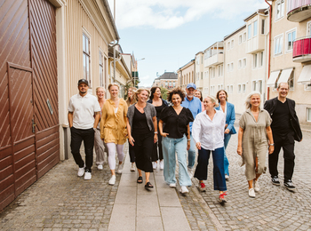En grupp vuxna människor går tillsammans på en stadsgata med bostadshus i bakgrunden.