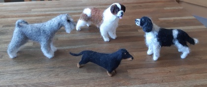 Fyra tovade hundfigurer i olika färger står på ett trägolv.