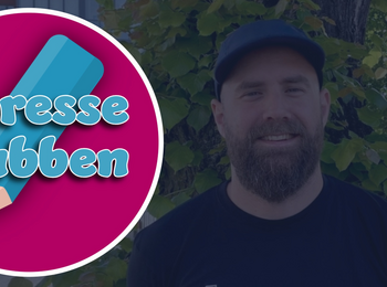 Logotyp för Lindesberg Intresseklubben med en blå penna på rosa bakgrund, utomhusmiljö med träd och parkering.