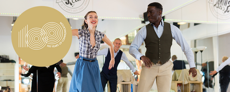 Två personer dansar tillsammans i en dansstudio med spegelvägg, glada och energiska.