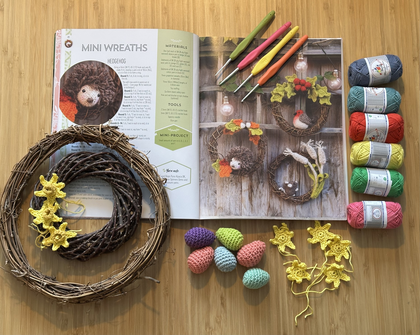 Material för att göra virkade mini-kransar: garn, virknålar, kransar, virkade blommor och ägg samt en instruktionsbok.