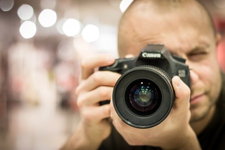 En person håller en kamera nära ansiktet och fotograferar mot kameran.