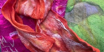 Färgglada textilier i orange, rosa och grönt med filtad och texturerad yta, liggande över varandra.