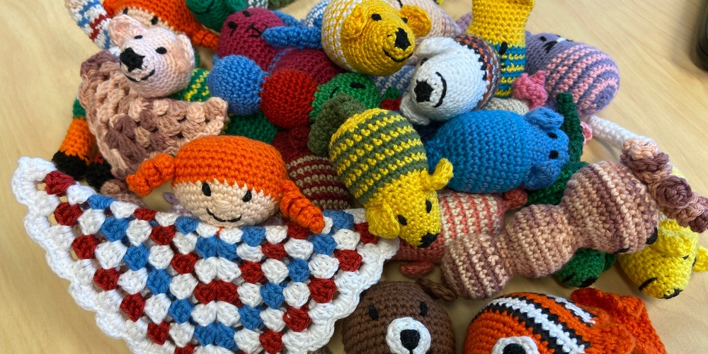 En hög med färgglada virkade mjukdjur och figurer på ett bord.