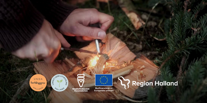 Händer tänder eld med tändstål på trä utomhus, logotyper för Halland och EU syns.