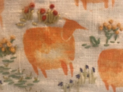 Mönstrat tyg med orange får och blommor i olika färger på ljus bakgrund.