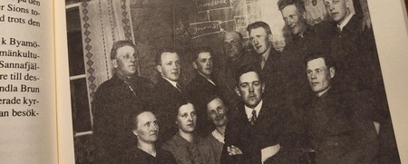 Uppslagen boksida med svartvit gruppbild av män i kostym från 1940-talet och svensk text om folkbildning.