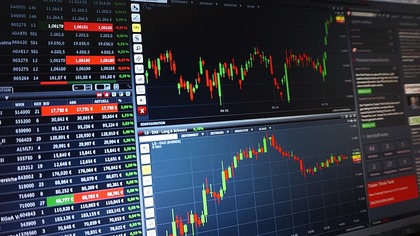 Datorskärm med aktiekurser, grafer och finansiell information i olika färger.