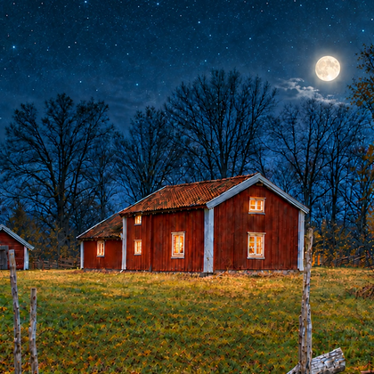 Röd stuga med tända fönster under stjärnklar himmel och fullmåne, omgiven av träd och trästaket.