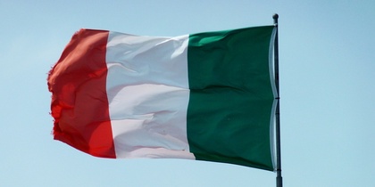 Den italienska flaggan vajar mot en klarblå himmel ovanpå en flaggstång.
