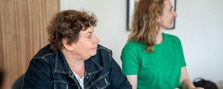 Två kvinnor sitter vid ett bord och antecknar under ett möte eller en workshop.