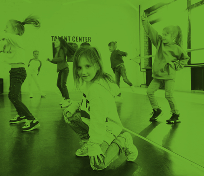 Barn dansar i en dansstudio med grönt filter över bilden. En flicka sitter på huk i förgrunden.