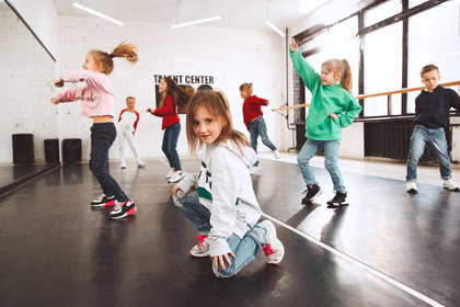 Barn dansar i en ljus dansstudio med stora fönster och spegelvägg.