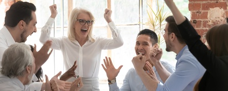 En grupp glada kollegor firar tillsammans runt ett bord på ett kontor.