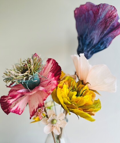 En bukett färgglada konstgjorda blommor i olika former och färger mot en ljus bakgrund.