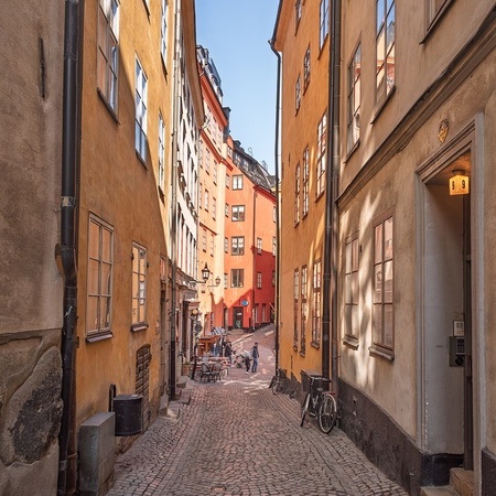 Smal kullerstensgata med färgglada gamla hus och några människor längre bort.