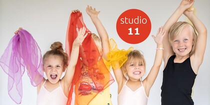 Fyra glada barn med färgglada sjalar poserar framför en vit bakgrund med texten 'studio 11'.