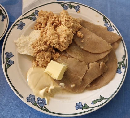 En tallrik med traditionell svensk mat: kolbullar, smör, messmör, grädde och ost på blåblommigt porslin.