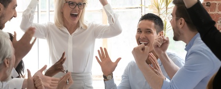 En grupp glada kollegor firar tillsammans runt ett bord på ett kontor.