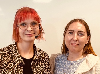 Två personer står bredvid varandra framför en vit tavla, ansiktena är suddade för anonymitet.