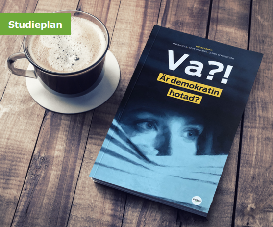 En kopp kaffe och en bok med titeln 'Va?! Är demokratin hotad?' ligger på ett träbord.