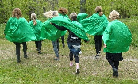 En grupp personer med gröna capar går i en skogsdunge.