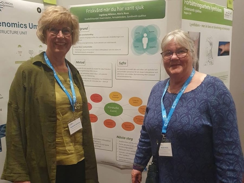 Två kvinnor står framför en utställningsposter på en konferens, båda bär namnskyltar och blåa band.