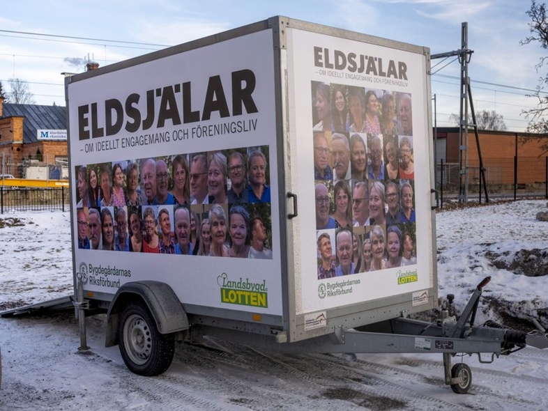 En släpvagn med reklam för 'Eldsjälar' står parkerad utomhus på en snötäckt mark.