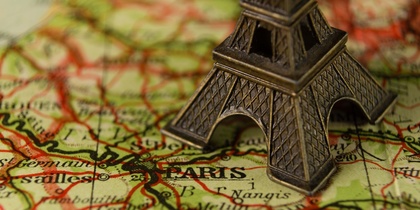 Närbild av en liten Eiffeltorn-modell placerad på en karta över Paris, Frankrike.