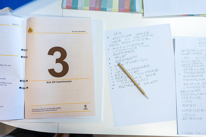 Bord med öppet häfte om kommunval och handskrivna anteckningar på papper.