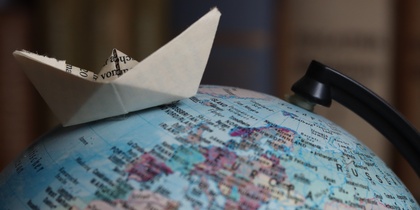 En pappersbåt står ovanpå en jordglob med fokus på Europa och Ryssland.