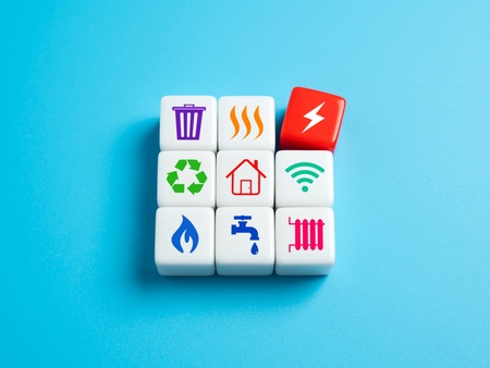 Nio kuber med ikoner för el, vatten, värme, återvinning och andra hushållstjänster på blå bakgrund.