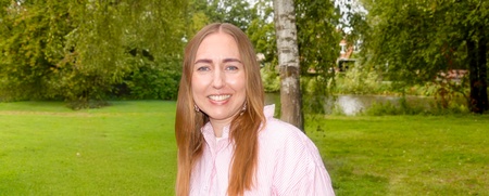 Porträtt på Cecilia, projektledare på SV Örebro län. Hon står utomhus, grön gräsmatta i bakgrunden, på sig har hon en röd- och vitrandig skjorta.  