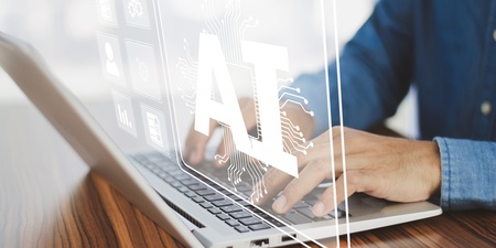 Person skriver på en bärbar dator med en digital AI-symbol projicerad ovanför tangentbordet.