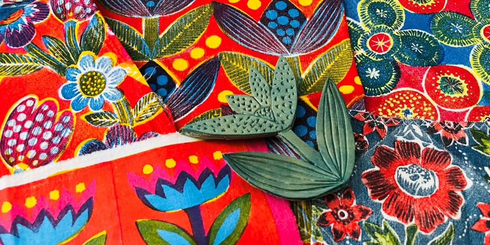 Färgglada tyger med blommönster och två gröna bladformade stämplar ovanpå.