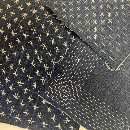 Flera tygbitar i blått med vita broderade mönster i olika geometriska former.