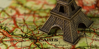 Närbild av en liten Eiffeltorn-modell placerad på en karta över Paris, Frankrike.