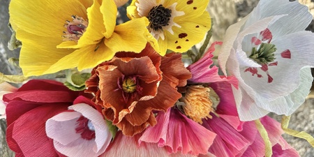 En bukett färgglada pappersblommor i olika former och färger, fotograferad ovanifrån.