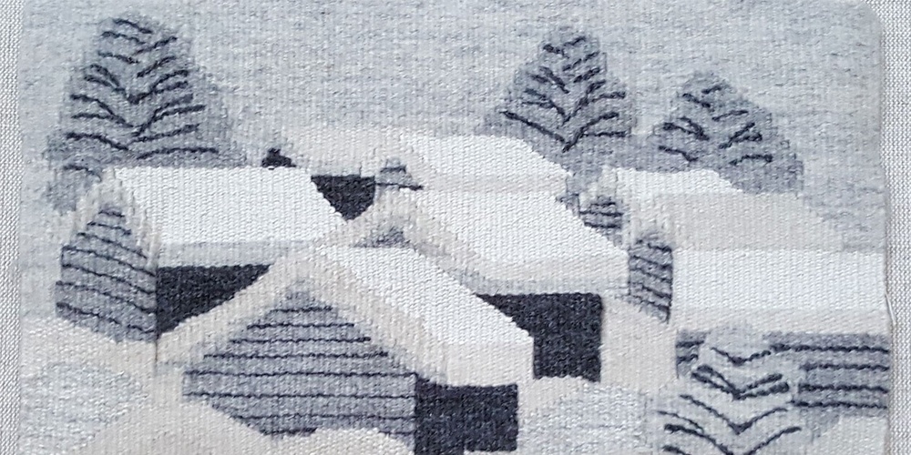 Vävd bild av snötäckta hus och träd i ett vinterlandskap, i grå och vita nyanser.