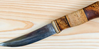 En kniv med trähandtag ligger på en ljus träyta.
