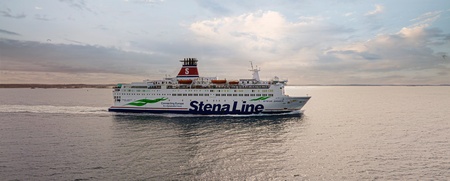 En Stena Line-färja seglar på ett lugnt hav under en molnig himmel vid solnedgång.