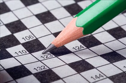 En grön blyertspenna pekar på en ruta i ett korsord med siffror.