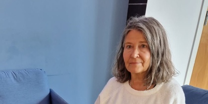 Kvinna sitter i ett vardagsrum bredvid ett soffbord med dekorationer av tyg och stenar.