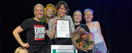 En grupp glada och unga personer som håller ett diplom och blombukett